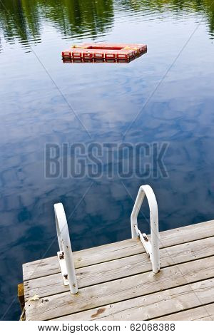 Dock and ladder on summer lake with diving platform in Ontario Canada