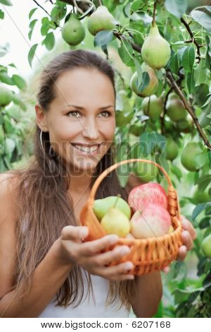Belle fille dans le jardin avec les pommes et les poires dans le lit