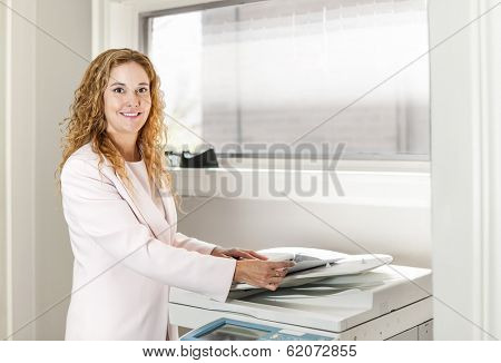 Smiling business woman operating photocopy machine in office