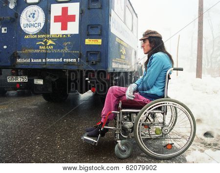 BIHAC, BOSNIA - NOV 19: A wheelchair bound man, wounded in fighting between Muslim and Serbian forces, sits beside a truck carrying food and medicine aid outside of Bihac, Bosnia, on Tuesday, November 19, 1995.