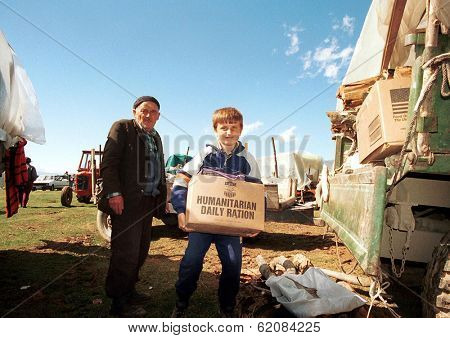 KUKES, ALBANIA, 17 APRIL 1999 --- A young  Kosovar Albanian refugee  returns to his camp in northern Albania with an aid packages distributed by the United States government.