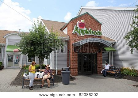 WOODBURY COMMON - JULY 9: Pedestrians walk past an Applebee's restaurant in Woodbury Common, New York, on Tuesday, July 9, 2013. 