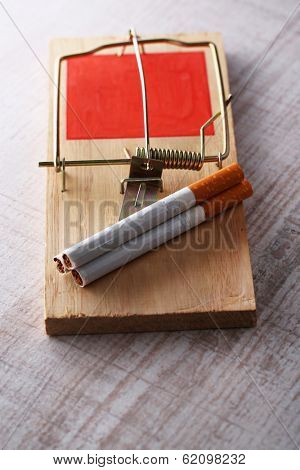 Mousetrap with cigarette, on wooden background