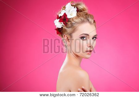Beautiful girl, isolated on a pink background with varicoloured flowers in hairs, emotions, cosmetics