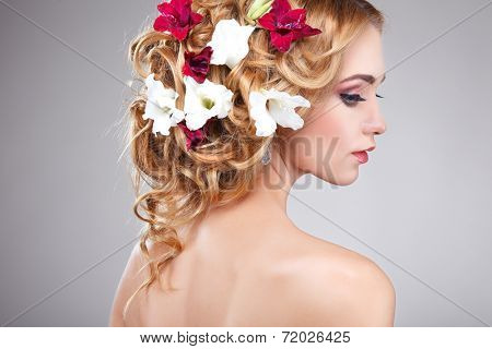 Beautiful girl, isolated on a light - grey background with varicoloured flowers in hairs, emotions, cosmetics