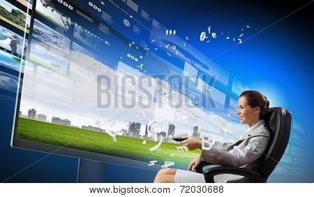 Young businesswoman in chair near tv screen with click