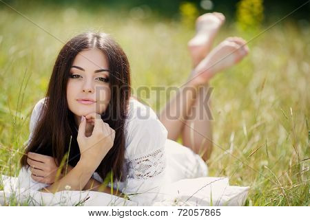 Girl resting on the soft pillow in fresh spring grass.