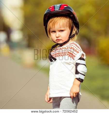 two year old pretty girl in  a helmet on the street close-up