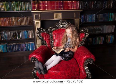 Girl reading book at home. Child in library