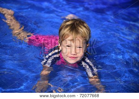 Swimming lessons: Cute baby girl is learning how to swim in the pool