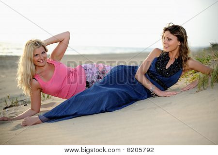Two Young Girls Friends Relaxing On The Beach Togather