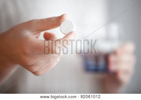 White Round Pill And Glass Of Water In Womans Hand