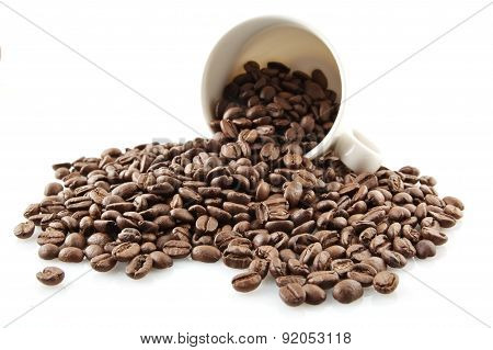 Overturned Cup Full Of Coffee Beans On White