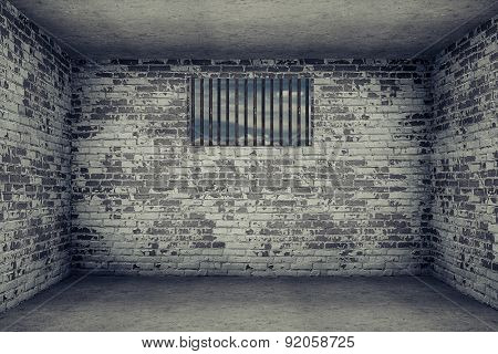 old dark room with brick wall and small window with metal grating
