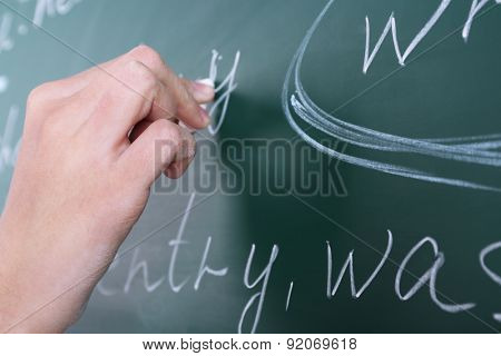 Female hand writing sentences on blackboard with chalk close up