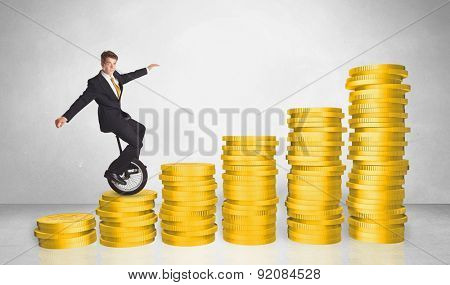Business man riding monocycle up on coin graph concept on background