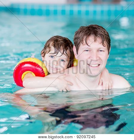 Young Dad Teaching His Little Son To Swim Indoors