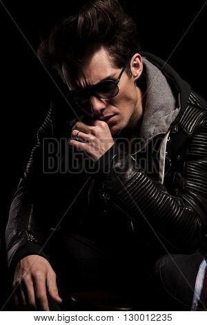 dramatic thinker in leather jacket and sunglasses posing in studio