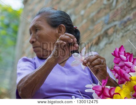 PANCHIMALCO EL SALVADOR - MAY 08 : A Salvadoran woman decorates palm fronds with flowers during the Flower & Palm Festival in Panchimalco El Salvador on May 08 2016
