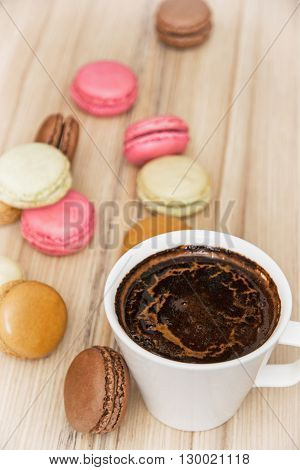 Cup of black coffee with french colorful macarons. Sweet delight. Vertical composition. Food and drink. Tasty macarons. Sweet food.
