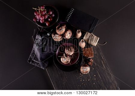 Italian maroni cookies on the plate and bowl with grapes chocolate milkshakes cloth notebook on dark old wooden background from the top