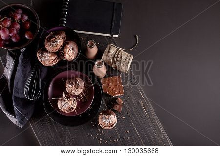 Italian maroni cookies on the plate and bowl with grapes chocolate milkshakes cloth notebook on dark old wooden background top view