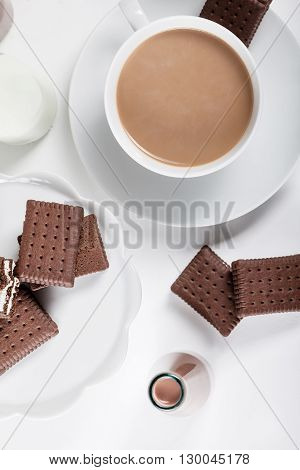Cup of coffee and few bottles of milk and chocolate milkshakes on white shutters background from the top