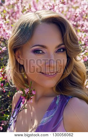young girl a pink little flowers of almond tree Amygdalus  in Sunny day