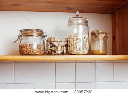 real comfort wooden kitchen with breakfast ingredients close up in glass, honey, oatmeal, milk, muesli