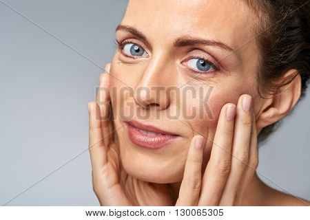 Attractive woman touching her face, mature beauty concept