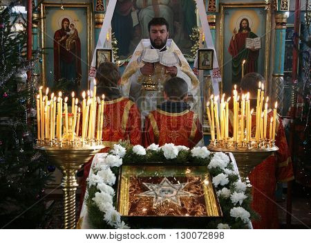 VOYUTYN UKRAINE - JANUARY 08: Orthodox priest and little sextons during holiday prayers in Voyutyn on January 08 2009.
