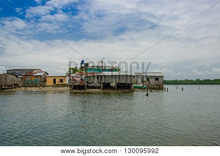 Muisne, Ecuador - March 16, 2016: Muisne town as seen from water, modest wooden houses sitting on poles waterfront pacific ocean, city buildings background and beautiful blue sky.
