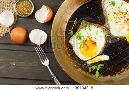 Fried fried egg on steel pan. Preparing homemade dietary supplements. Pan on a dark wooden table. Fried eggs.