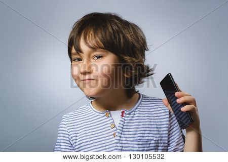 Portrait of happy boy with mobile going surprise on gray background.