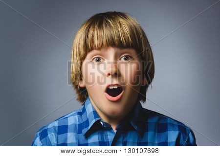Portrait of happy boy going surprise on gray background.