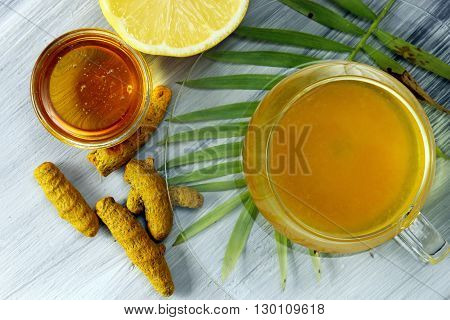 Healthy Haldi or Turmeric with honey and lemon antioxidant tea on a grey background.