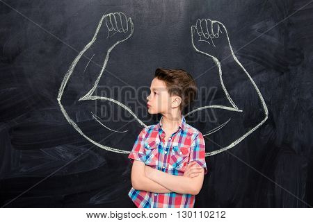 Little boy looking at muscles drawn on blackboard