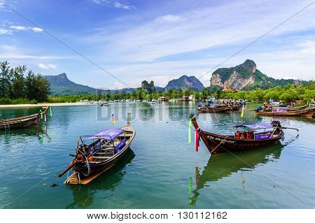 Hat Noppharat Thara Thailand - January 5 2013: Long-tail boats for tourist trips moored in bay with limestone karsts on horizon at Hat Noppharat Thara in Krabi Province southern Thailand