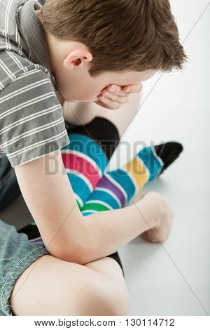 Grieving Boy Sitting Cross Legged Covers His Eyes