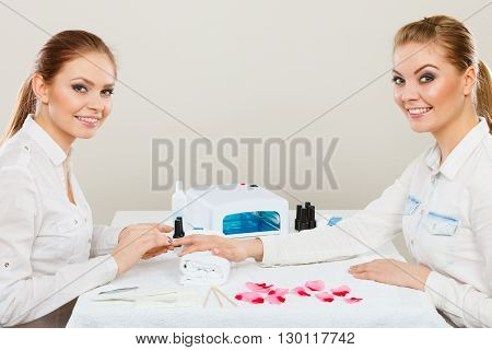 Relaxing time and wellness day concept. Blonde elegant woman visiting professional manicurist salon. Beautician makes perfect nails to client.