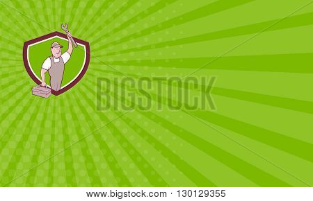 Business card showing illustration of a mechanic wearing hat and overalls lifting raising up spanner wrench holding toolbox looking to the side viewed from front set inside shield crest on isolated background done in cartoon style.