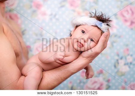 The baby girl is on hand to dads looking and smiling into the camera