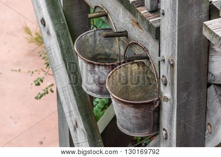 A photo with two rusty bucket on the wall