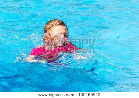 Photos with a child in a red t-shirt playing in the pool. Part of the face covered blue water.