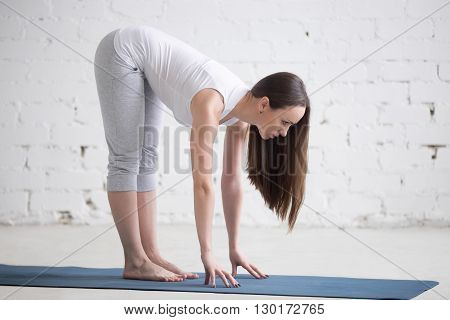 Attractive Fit Young Woman Doing Ardha Uttanasana Pose In White Loft
