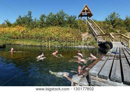 NALYCHEVO NATURE PARK, KAMCHATKA PENINSULA, RUSSIA - SEP 7, 2013: Group hot springs in Nalychevo Nature Park - tourists take a therapeutic (medicinal) baths in pool with natural thermal mineral water having balneological properties.