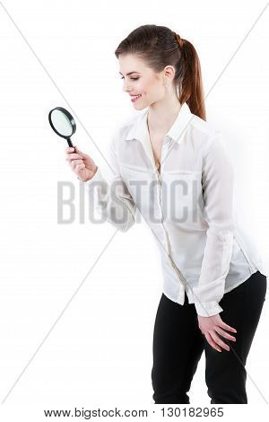 Young attractive business woman looking into a magnifying glass