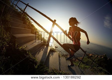fitness woman trail runner running on seaside mountain stairs training for cross country running.