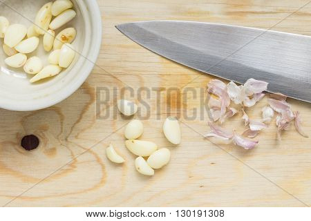 Peel garlic with sharp knife on wood board
