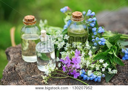 Essential aroma oil in bottles on wooden background outdoor. Selective focus. Natural ogranic products.